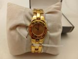 an image of a gold watch sitting on top of a pillow