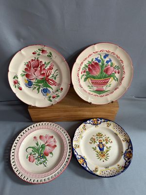 trois assiettes ornées de motifs floraux, posées sur un support en bois