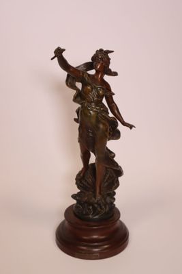 statue en bronze représentant une femme tenant un oiseau, posée sur un socle en bois