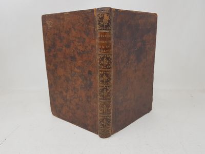 an old book with a brown cover sitting on a white surface