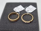 two gold rings with diamonds on them sitting on top of a black cloth