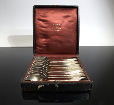 six silver spoons in a case on a table