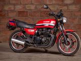a red and black motorcycle parked in front of a brick wall