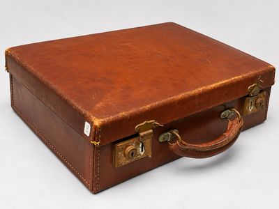 a brown suitcase sitting on a white surface