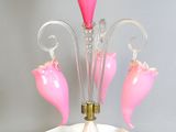 a pink glass vase with flowers on it on a table