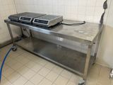 une table en acier inoxydable sur laquelle sont posés deux fours, dans une cuisine