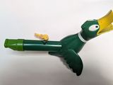 a green and yellow toy bird that is on a white surface