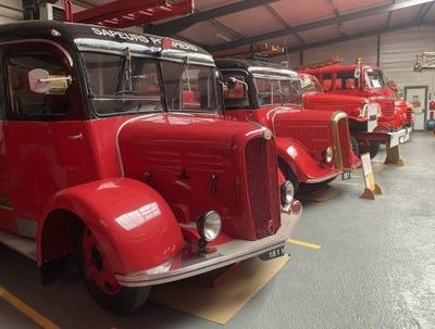 row of red fire trucks parked in a garage next to each other