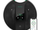 un aspirateur robot noir et vert à côté d'un iPhone