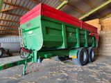 un camion-benne vert et rouge garé dans une grange