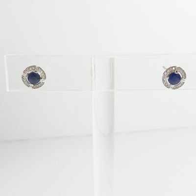 pair of sapphire and diamond stud earrings on clear acrylic stand