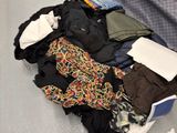 une valise pleine de vêtements et des vêtements par terre