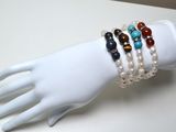 une main de mannequin blanche tenant un bracelet orné de perles multicolores