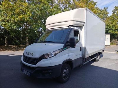une camionnette blanche garée sur un parking avec des arbres en arrière-plan