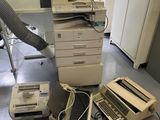 un tas de vieux ordinateurs et une imprimante posés par terre