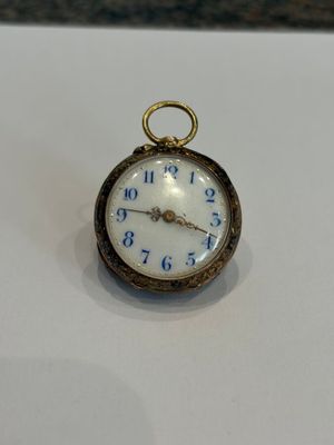 une petite montre de poche posée sur une surface blanche