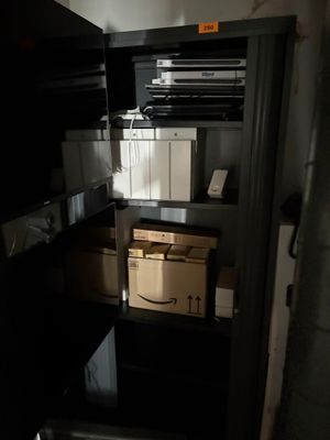 une porte ouverte donnant sur une petite pièce où se trouve une étagère remplie de cartons