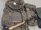 a large backpack with a gun and a rifle on the ground