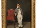portrait of a young boy in a suit and bow tie standing next to a red chair