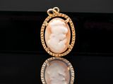 a close up of a gold plated pendant with an image of a woman