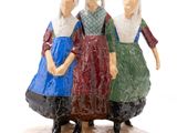 three figurines of women standing on a wooden base