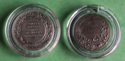 two silver coins in a glass container on a green surface