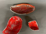 three pieces of red glass sitting on a table