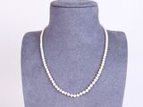 a white pearl necklace on a mannequin neck
