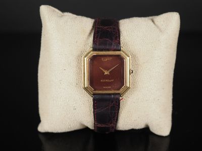 une photo d'une montre posée sur un oreiller, lui-même posé sur une table