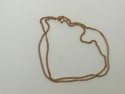 a close up of a gold necklace with a chain on a white surface