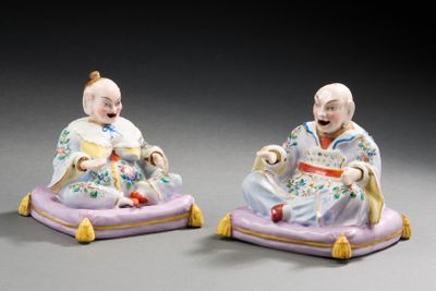 paire de figurines en porcelaine représentant un homme et une femme assis sur un coussin violet