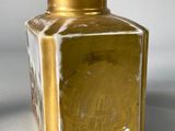 a gold vase sitting on a table with a white wall in the background