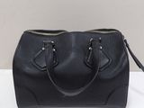a black handbag sitting on top of a white table