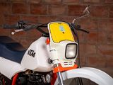 a white and orange motorcycle parked in front of a brick wall