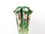 a green vase with flowers on it on a white background