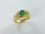 gros plan d'une bague en or avec une pierre verte et des diamants