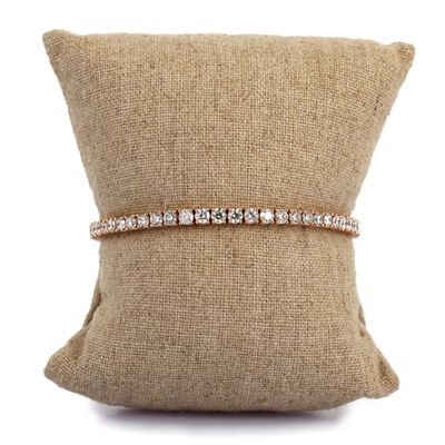 un bracelet en diamants posé sur un coussin, sur fond blanc