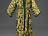 une robe verte et dorée posée sur un présentoir pour mannequin