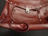 a brown purse with rivets on it sitting on a black surface