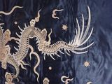 a dragon that is on a black cloth with gold thread