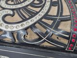 a close up of a clock with red jewels on it