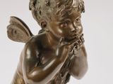 an antique bronze statue of a little boy with a flute