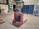 un chariot élévateur rouge dans un entrepôt où se trouvent des casiers bleus