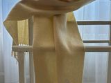 a yellow scarf hanging on a clothes rack in front of a window