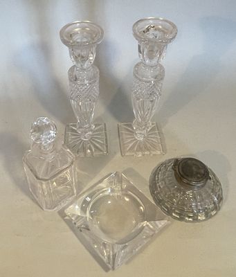 three glass candlesticks and a glass ashtray on a table