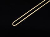 a gold necklace with a chain on a black background