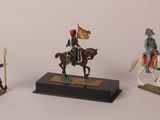 three figurines of soldiers on horses and a man on a horse