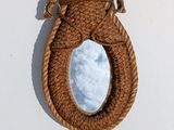 a mirror hanging on the wall with a rope around it