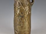 un vase antique en bronze orné d'une femme et d'un oiseau
