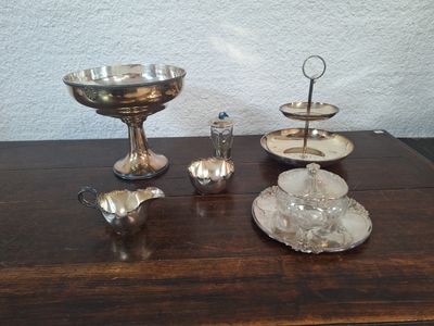 une table en bois sur laquelle sont posés des plats et des tasses en argent